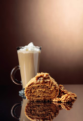 Walnut cake and coffee latte with cream on a reflective background.
