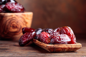 Juicy dates in a old wooden dish.