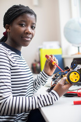 Portrait Of Female Teenage Pupil Building Robot Car In Science Lesson