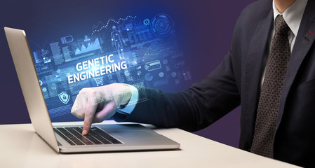 Businessman working on laptop with GENETIC ENGINEERING inscription, cyber technology concept