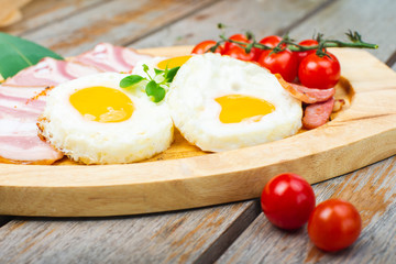 Fototapeta na wymiar Tasty fried eggs with vegetables on a wooden plate.