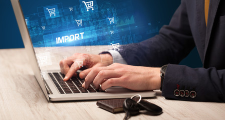 Obraz na płótnie Canvas Businessman working on laptop with IMPORT inscription, online shopping concept