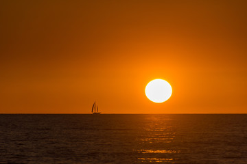 Sunset with a sailing boat on the horizon