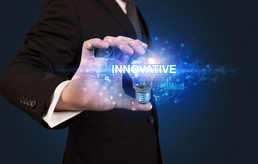Businessman holding light bulb with INNOVATIVE inscription, innovative technology concept