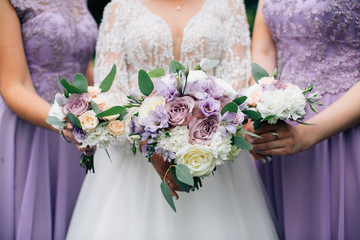 Bride and bridesmaids holding wedding bouquetes - Powered by Adobe