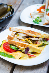 Classic breakfast, hot sandwiches with cheese, vegetables and chicken on a wooden table.