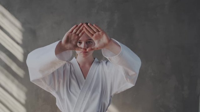 A girl performs a traditional taekwondo stance. Her arms are extended at face level, open palms, look into the camera. Southern martial arts, fighter gestures, martial arts.