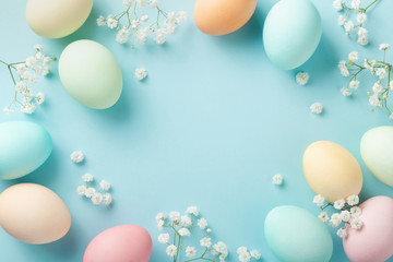 Pastel Easter eggs on blue background top view. Flat lay style.