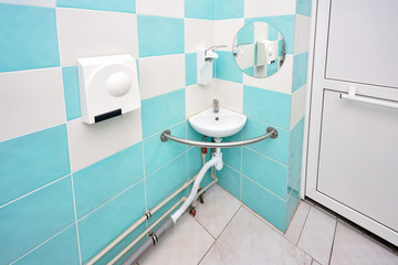 Interior of specially adapted bathroom toilet with friendly design for people with disability handicapped with disabilities or invalids in wheelchair with handrail handle bar sink hand dryer