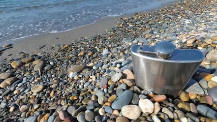 vintage metal hip flask on pebbles on a beach. celebration of men's holiday at sea. conception International Men's Day and Fatherland defender day February 23. copy space