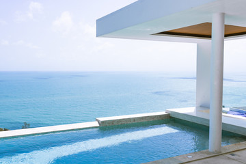 Fototapeta na wymiar View of the villa and sea landscape with a blue pool in a minimalist style. Rich and luxurious life in the tropics of the island