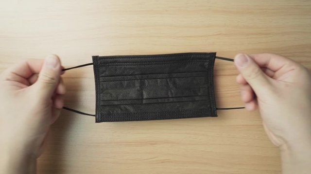 Hand pulling an elastic black mask string. Tutorial how to wearing a mask to prevent corona virus.