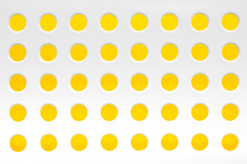 White plastic background with regular holes on yellow background. Copy, empty space for text