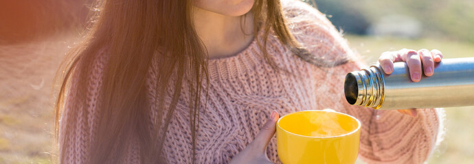 Portrait of pretty young woman in stylish knitted sweater standing on the golden autumn forest on sunny day, Time to relax and have some coffee