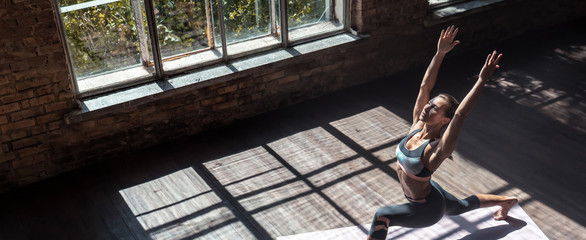 Top view young healthy sporty slim woman keep fit do practice hatha yoga instructor training Virabhadrasana I warrior 1 posture balance pose modern gym mat wooden floor concept copy space, banner