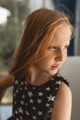 Little girl with red hair shows different emotions. Sadness, joy and happiness. She smiles and cries. In a black dress with skin pigment on her face, freckles