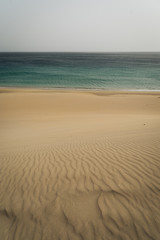 Very calm shot of beach with textured sand hills and blue water