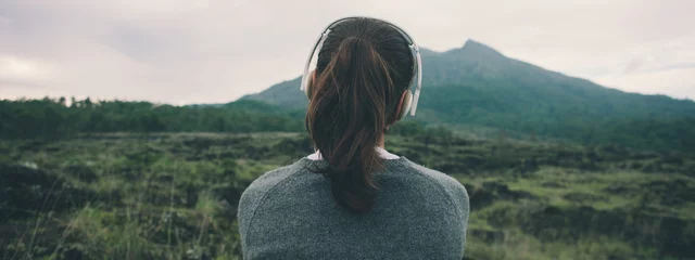 Foto op Canvas Woman in headphones listening music in nature and at the mountain © Alex from the Rock