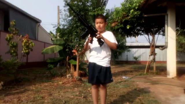 The boy was playing with a fake gun toy in the front yard.