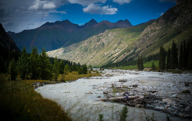 A muddy river flowing in narrow valley in Tianshan Mountains across Central Asia