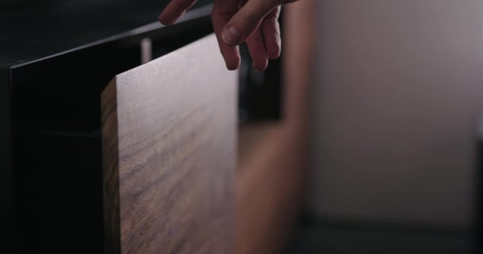 Slow motion man hand open and close tv stand drawer closeup