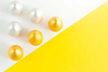 Gold and silver eggs on a white and yellow background. Minimalistic composition. Easter holiday card.