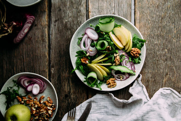 Vegetarian salad of fresh apples with arugula, onions and nuts in a plate on the table