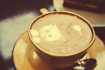 green cup with cappuccino coffee close up. A cat and a heart are drawn on the foam. On a brown table is a mug with hot tasty coffee. latte art decoration. break time concept