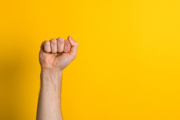 close up man hand fist over a yellow background. winner and power sign