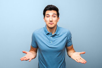 handsome brunette man in blue polo shirt with serious face gesturing with his hands against a blue background. studio shoot. there is nothing to do