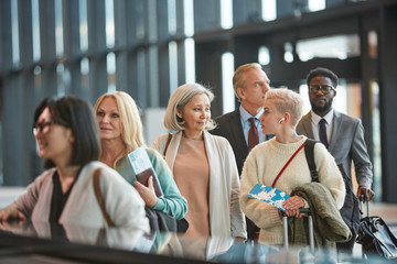 Fototapeta na wymiar Two women chatting while standing in airport customs queue, horizontal medium portrait, copy space