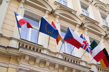 National flags and flag of European union are waving on the pole. Facade of historical building with national symbols and sign of EU.