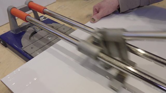 Tile cutter.Builder-tiler working with floor tile cutting equipment .