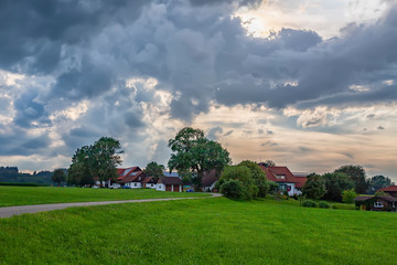idyllic landscape with greenfield, road, and traditional german farmhouses.