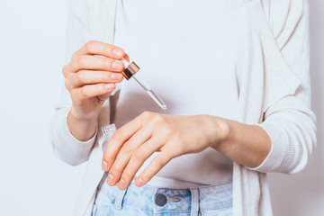 Young woman holding bottle of cosmetic serum