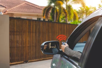 Fotobehang Woman in car, hand using remote control to open the auto gate when driving and arrive home. Automatic door, security system and wireless concept. © NIKCOA