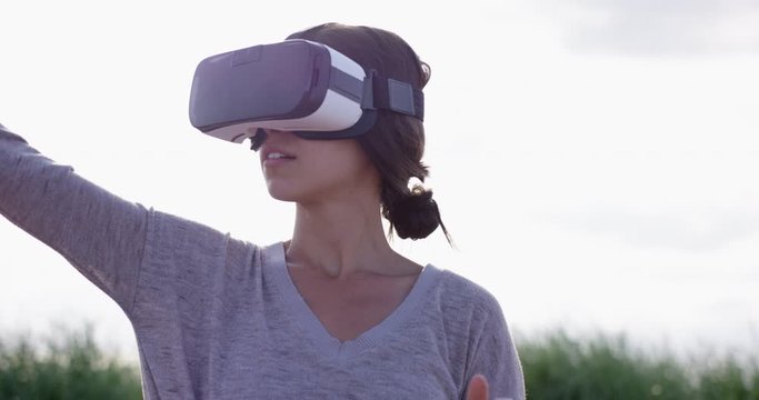 Woman tapping on virtual screen while wearing VR AR goggles outdoors - close up