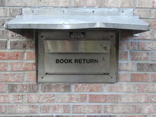 exterior public library book return slot in brick wall