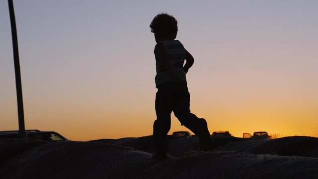 Silhouette of a child running in the country at sunset
