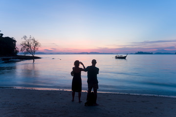 Silhouette of tourist is watching beautiful sunset on the beach in Krabi, Thailand during summer vacation time. 