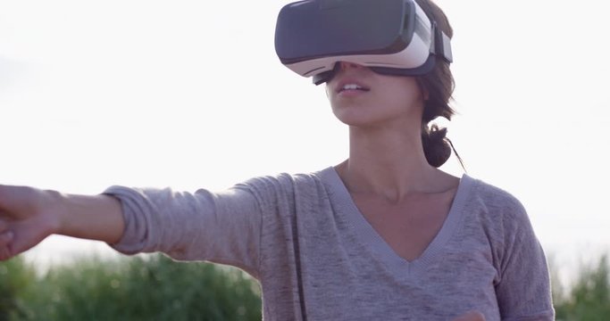 Woman scanning virtual space while outdoors and wearing VR goggles - close up