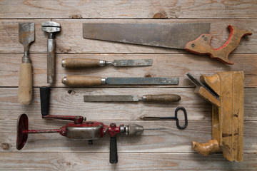 Vintage woodworking tools on a wooden background. Chisels, rasps, plane, puncher and a hand drill...