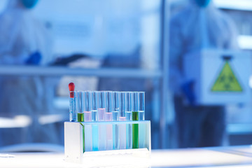 Horizontal shot of test-tubes with coloured liquids on desk in modern laboratory, copy space
