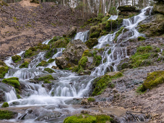 Fototapeta na wymiar A stream of water flowing over rocks and creating a waterfall effect.