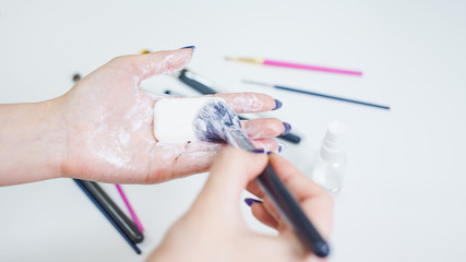 Cleaning and care of makeup brushes, women's hands wash the brush from cosmetics,