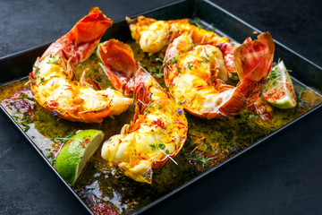 Traditional barbecue spiny lobster tail sliced and offered with saffron lemon sauce as closeup in a...