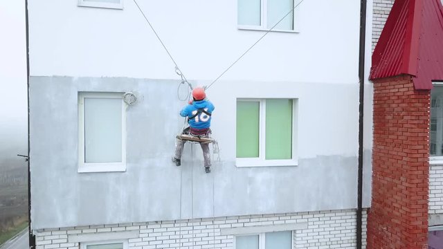 Industrial climber paints the facade of a new building