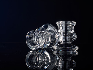 Glass candlesticks with lit red candles stand on black glass