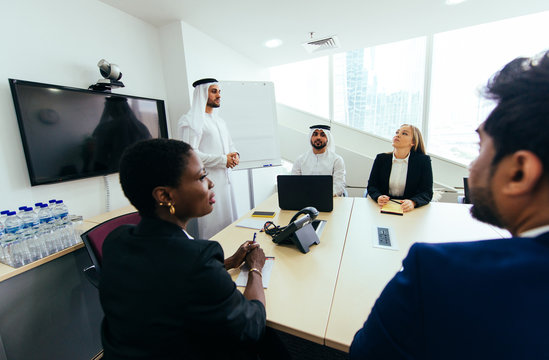 Mixed business team in Dubai. Business meeting with men wearing kandura and western people in the office