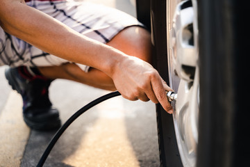 Obraz premium Close up of asian man inflating tire in the gas station.